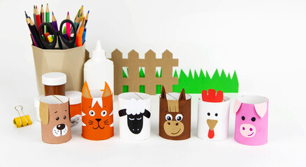 Children's crafts farm pets from toilet sleeves. View from above on diy of farm animals: horse, sheep, scrolls, rooster, dog, cat. Instruction step by step with the child's paper.
