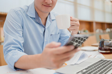 business man drinks coffee and checks news, social media on phone.