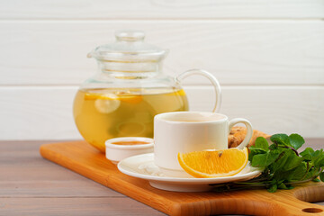 Cup of tea with ginger and mint on wooden table
