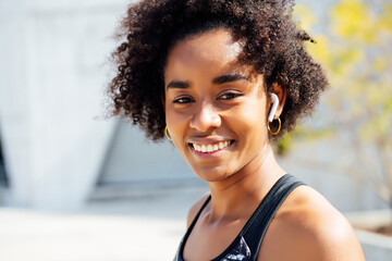 Afro athletic woman standing outdoors.