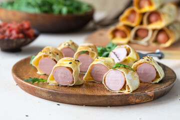 Homemade sausages in dough with sesame served with tomato sauce, light stone background. Pigs in blanket. Fast food.