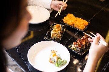  Girl holds chopsticks and Sushi roll .