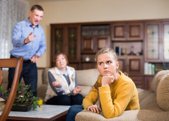 Portrait of upset girl scolded by parents at home. High quality photo
