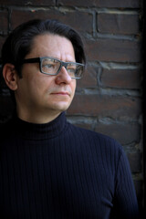 Obraz premium A man with glasses on a brick wall background. Scientist. Psychological picture.