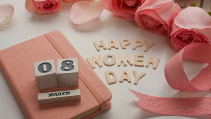 8 March Happy Women's day on white table decorated with pink flowers, ribbon and notebook