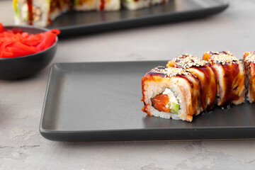 Dragon sushi roll with eel on black ceramic plate
