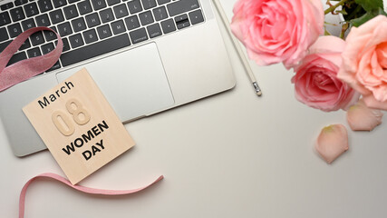 8 March Women's Day on workspace with laptop, pencil and pink flowers on the table