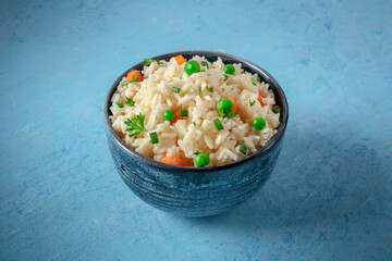 Rice with veggies on a blue background, healthy side dish