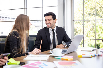 Male office workers chatting happily with young colleagues in the conference room.
