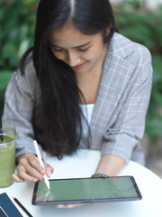 Businesswoman relaxing with digital tablet on coffee table in garden