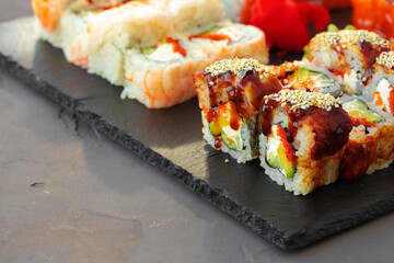 Set of various sushi rolls served on gray background