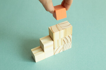 Hand stacking wood block stairs on green background. Business development, growth, success concept