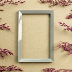 Empty photo frame with pink misty blue dry flowers on brown kraft paper background. top view, copy space