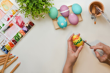 Female hands painting on eggs to prepare for Easter festival on craft table
