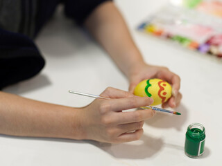 Female hands painting on eggs to prepare for Easter festival on craft table