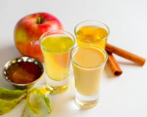 Fresh organic apple cider with apples and cinnamon over white background. Close up three glasses.