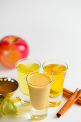Fototapeta premium Fresh organic apple cider with apples and cinnamon over white background. Close up three glasses.