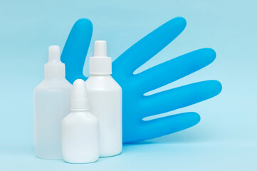 White plastic bottles of medicines and medical glove on a blue background