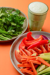 Platter of assorted fresh vegetables cut. Healthy raw veggies salad. Over orange background.