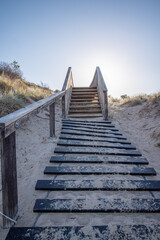 Erosion control stairs leading up a sand dune towards a bright blue sky. Exercise and the environment, portrait orientation.
