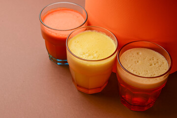 Isolated citrus juice. Three glasses with orange, grapefruit and lemon juice isolated on orange background.