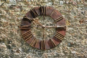 An Antique Metal Clock with Roman Numbers on a Stone Wall