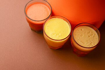 Isolated citrus juice. Three glasses with orange, grapefruit and lemon juice isolated on orange background.