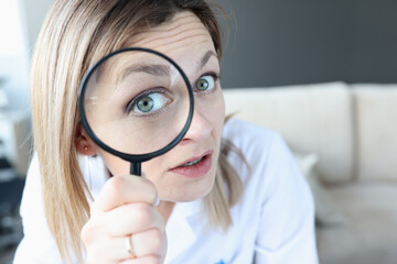 Woman doctor looking through magnifying glass closeup