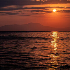 orange fiery sundwn sky with some clouds over calm sea, nature background