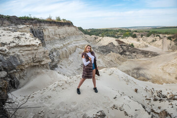 Young woman with casual cloth and fur coat, outdoor shoot near sand rocks