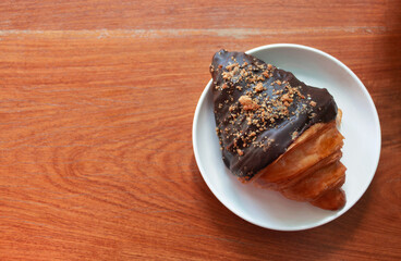 chocolate coated croissant on white plate on wooden table