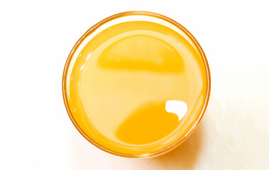 Transparent glass with orange nectar on a white background.