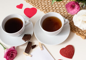Magic mood atmosphere of love picture for post in Instagram. Two cup of tea or coffee with chocolate and hearts on white table with brown napkin. Free minute at work and enjoyment from rest. Close-up