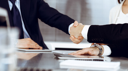 Business people shaking hands after contract signing in modern office. Teamwork and handshake concept