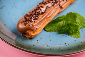 Tasty eclair with chocolate filling over pink background. French cuisine concept, dessert for tea...