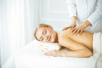 Beautiful happy woman enjoying back massage with closed eyes. Beauty and Spa salon concept