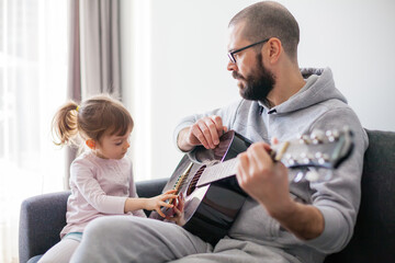 Little girl touching strings of the guitar