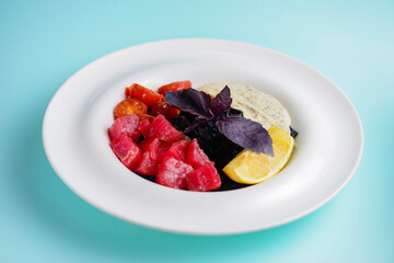 A plate with black homemade pasta with salted salmon, served on a blue background table.