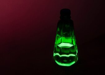 A green glass jar, a bottle with a turtle pattern and an illuminated bottom on a dark background