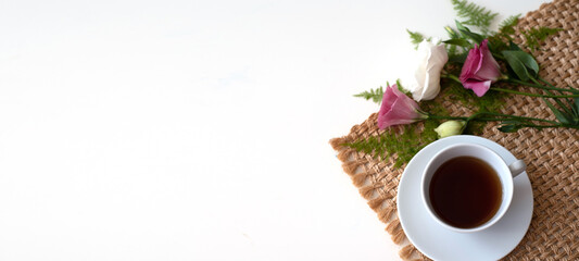 Cup of coffee with flowers and green branches on brown napkin. Short break from business work, beautiful picture for post in Instagram. Relax and have cup of coffee, enjoy your free minutes. 