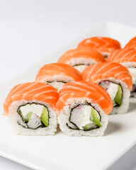 Maki Sushi - Roll made of smoked salmon and cream cheese. Traditional Japanese cuisine concept, over white background.