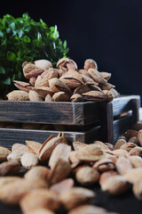 Salted almonds in shell. Delicious appetizer. Nuts in a wooden box. A large number of nuts are scattered on the table. Out of focus. Vertical photo.