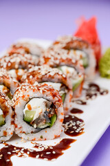 Japanese sushi set with eel and unagi sauce. Cream cheese inside. Served on a white plate.