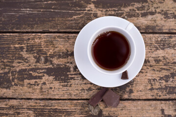 Cup of coffee with chocolate on wooden table. Fresh, aromatic drink is pleasant to drink to keep you awake in morning and during break at work. Close-up. 