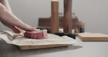 man massaging new york steak with spices on countertop