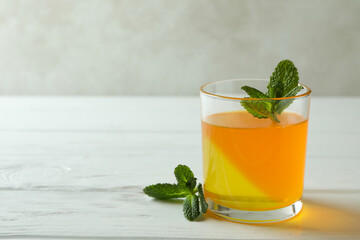 Glass of orange jelly with mint on white wooden table