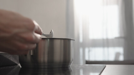 man hand stir fettuccine in boiling water in saucepan