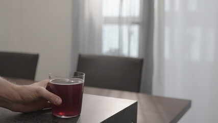 man hand take purple drink in tumbler glass from concrete countertop with copy space