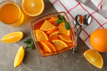 Fototapeta na wymiar Concept of dessert with bowl of orange jelly with orange slices on gray table
