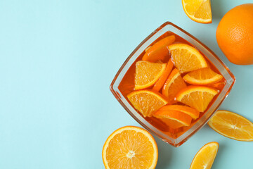 Naklejka na ściany i meble Bowl of orange jelly with orange slices on blue background